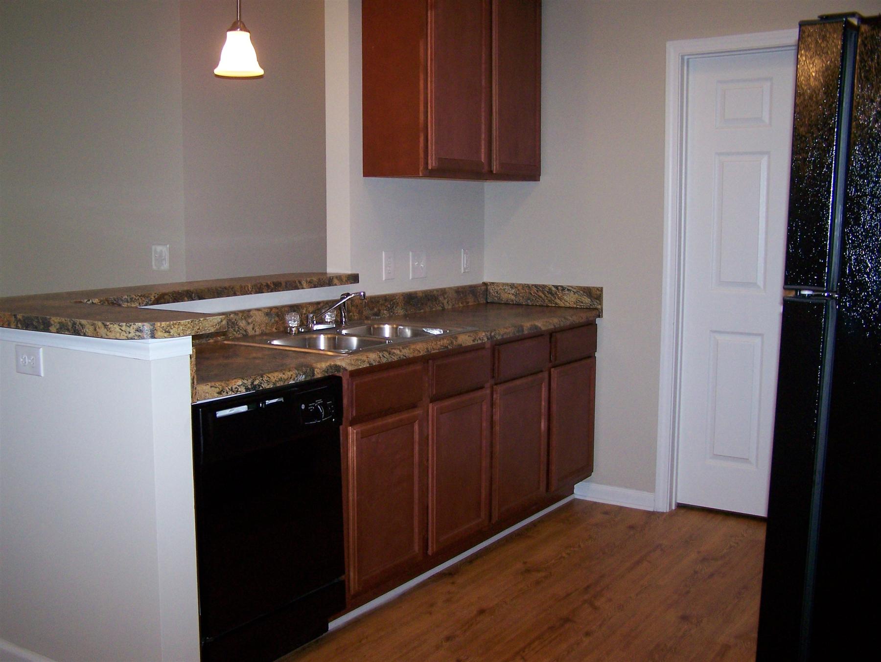 Kitchen with breakfast bar, black appliances and brown cabinets.