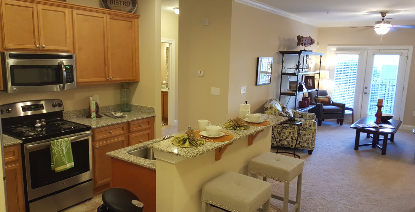 Living room and kitchen with an island, stainless steel appliances and granite countertops.